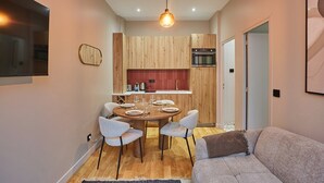 Une cuisine moderne avec des meubles de rangement en bois, une table à manger avec des chaises et un luminaire suspendu.