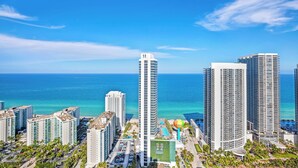 Un hôtel de grande hauteur offrant une vue sur l’océan, doté de nombreux balcons et d’un espace piscine.