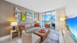 Une chambre d’hôtel moderne avec une grande fenêtre, un canapé, une table basse et des œuvres d’art accrochées au mur.