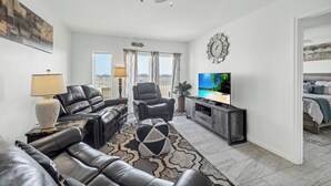 A modern living room with leather sofas, a TV, and a large window with curtains. - Spacious beachfront condo with community pool, located on the first floor of the (Port Aransas)