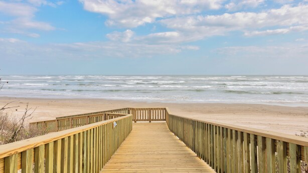 A wooden boardwalk leading to a beach with waves. - Spacious beachfront condo with community pool, located on the first floor of the (Port Aransas)