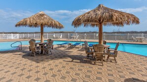 A poolside area with thatched umbrellas, lounge chairs, and a pool. - Spacious beachfront condo with community pool, located on the first floor of the (Port Aransas)
