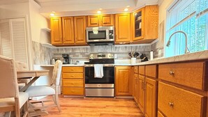 A modern kitchen with wooden cabinets, stainless steel appliances, and a marble backsplash. - 2Bed1 bath Near Ithaca &Cornell lower unit (Locke)