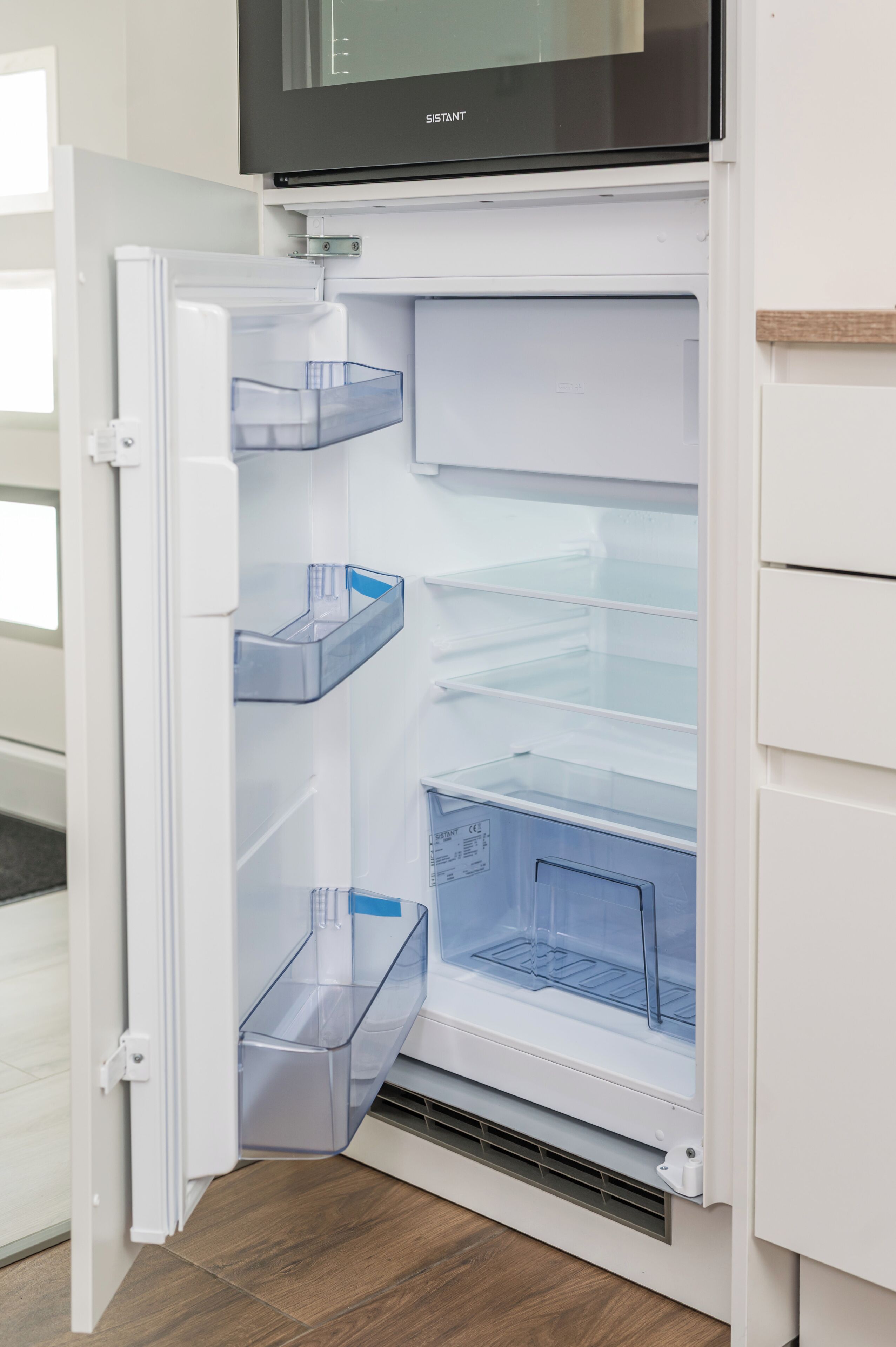 Un refrigerador abierto con contenedores de plástico transparente y un dispensador de hielo incorporado.