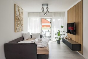 Una habitación de hotel moderna con cama, sofá, televisión y balcón con vistas.