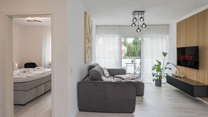 A modern living room with a grey sofa, a flat-screen TV, and a wooden accent wall.
