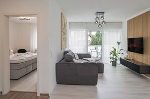 A modern living room with a grey sofa, a flat-screen TV, and a wooden accent wall.