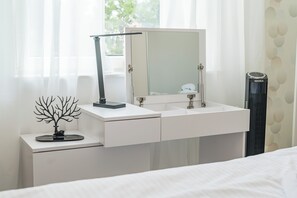 Habitación de hotel con cama, mesita de noche con espejo, un pequeño árbol decorativo y un calentador portátil.