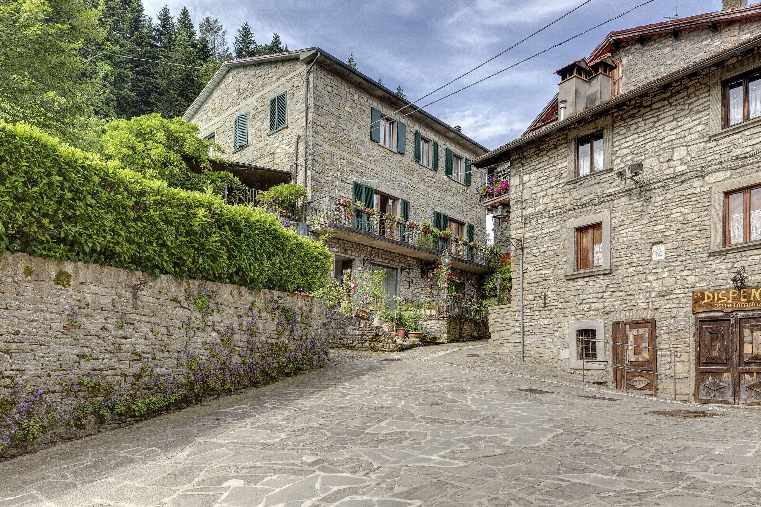 A stone building with a sign reading "La Dispenza della Locanda."