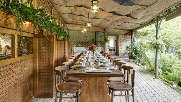 A long wooden table set for dining with chairs, surrounded by a wooden lattice wall and potted plants. - AMORE RENTALS - Villa Barbara with Private Pool and Garden (Palazzuolo sul Senio)