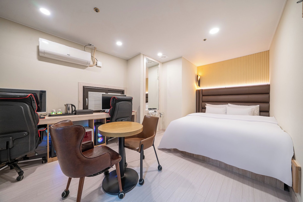 Una habitación de hotel con cama, escritorio, sillas y una pequeña mesa.