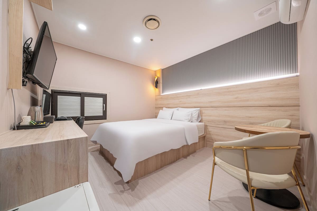 Een moderne hotelkamer met een bed, een bureau, een stoel en een televisie.