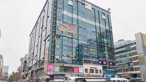 Un bâtiment moderne à plusieurs étages, doté de grandes fenêtres en verre et de diverses enseignes commerciales sur sa façade.