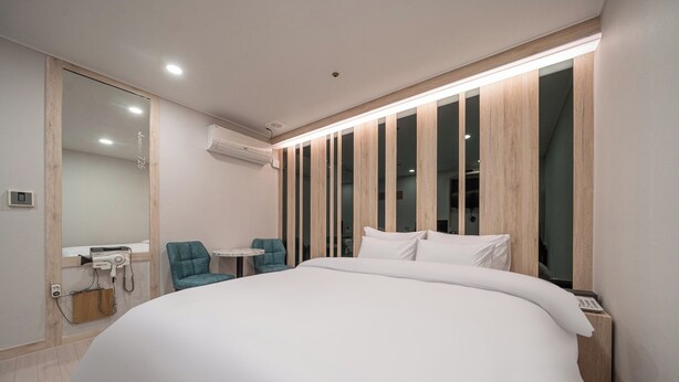 Une chambre d’hôtel moderne avec un grand lit, une petite table, une chaise et un miroir.