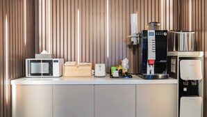 Une petite cuisine équipée d’un four à micro-ondes, d’un grille-pain, d’une machine à café et d’un distributeur d’eau.