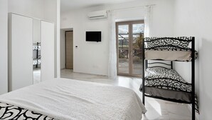 Ein Schlafzimmer mit Etagenbett, Flachbildfernseher, Kleiderschrank und einer Glasschiebetür, die auf einen Balkon führt.