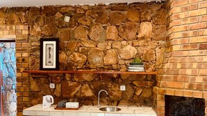 A kitchen with a stone wall, a sink, a tea tray, and a basket. - Casa da Namaacha

 (Naamacha)