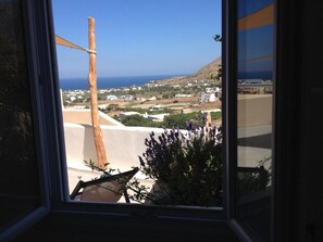 A view from a window overlooking a coastal landscape with buildings and a clear sky.