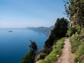 Un sentiero costiero con vista aperta sul mare e sulla terraferma in lontananza.