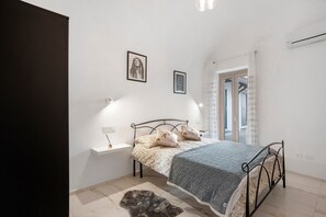 Une chambre à coucher comprenant un lit, une table de chevet, une lampe fixée au mur et deux tableaux encadrés.