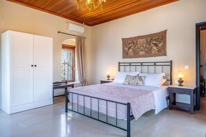 A bedroom with a bed, bedside tables, a wardrobe, a tapestry, and a chandelier. - Holiday Home 'Old Manor House 2' with Sea View, Wi-Fi and Air Conditioning (Syvota)