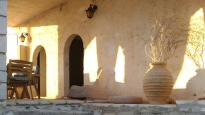 Eine Steintreppe führt zu einem Hauseingang, mit einem Holzstuhl und einer großen Vase.