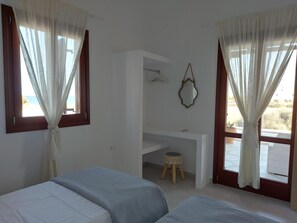 Een slaapkamer met twee bedden, een bureau, een spiegel en een klein krukje.