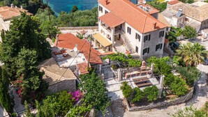 Un quartier résidentiel situé sur la côte, avec des maisons à étages, un sentier pavé de pierres et une vue sur la mer.