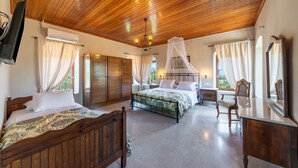 Une chambre à coucher avec deux lits en bois, une table de chevet, une chaise, un bureau et un grand miroir.
