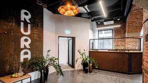 Ein modernes Interieur mit einer Rezeption, einem Holztisch mit Obstkorb und Gläsern sowie Topfpflanzen.