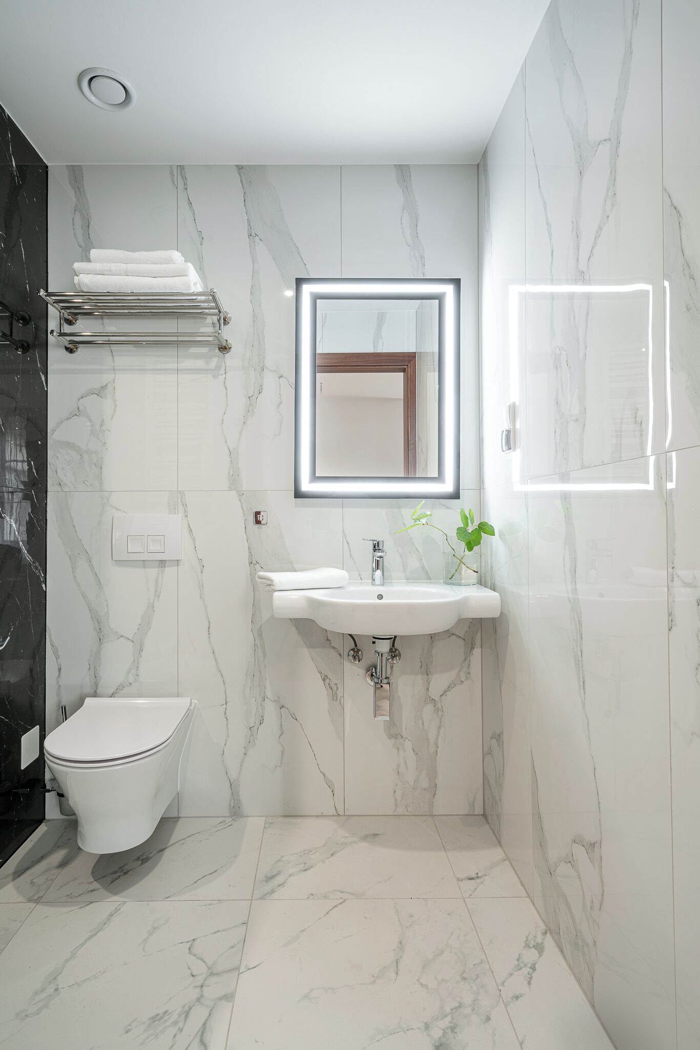 Un baño moderno con inodoro, lavamanos y toallero.