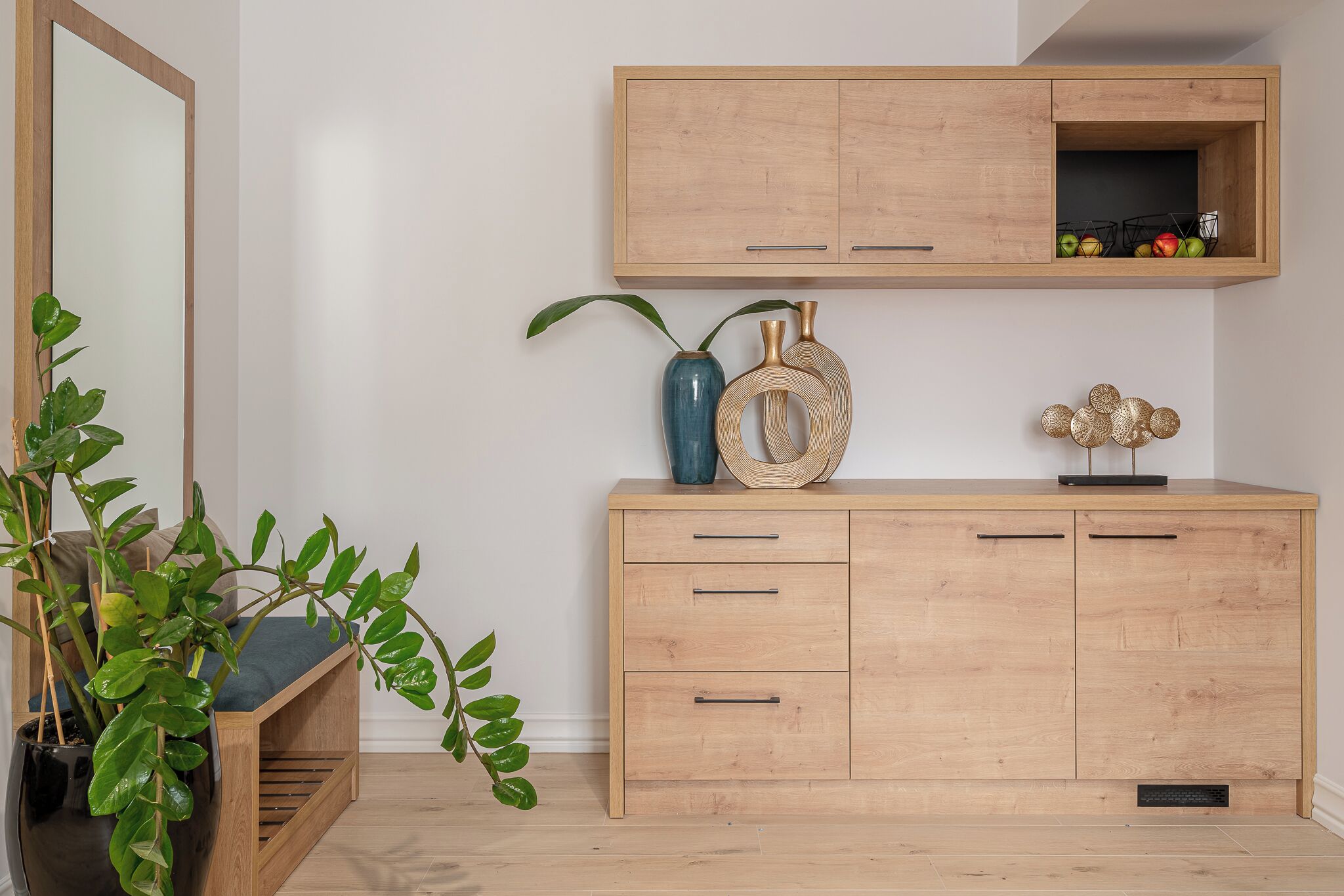 A wooden cabinet with drawers and a shelf, a mirror, and a potted plant.