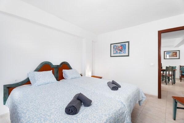 Une chambre à coucher avec un lit double, deux oreillers, une table de chevet, une chaise et une table à manger avec des chaises.