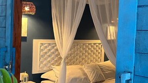 A bedroom with a canopy bed, a nightstand, a lamp, and a hanging light fixture. - Pousada La Vida Boutique (Amontada)