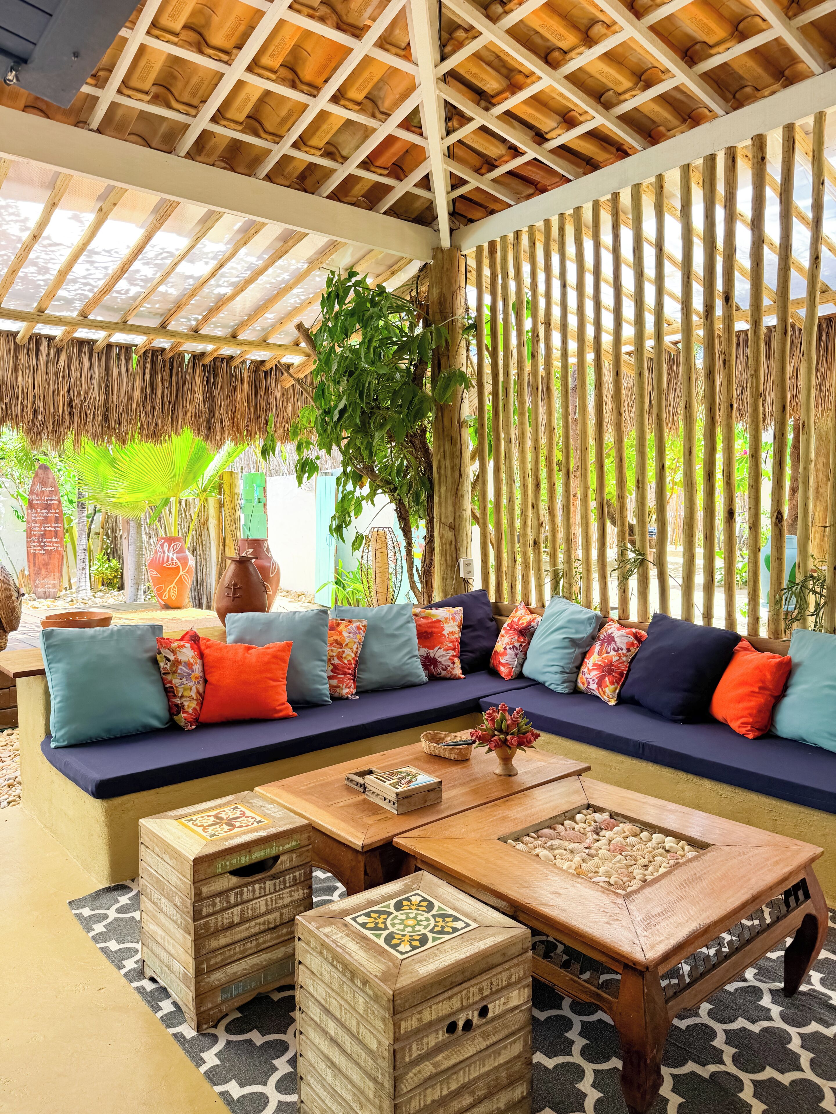 A covered outdoor seating area with a wooden bench, cushions, and a coffee table.