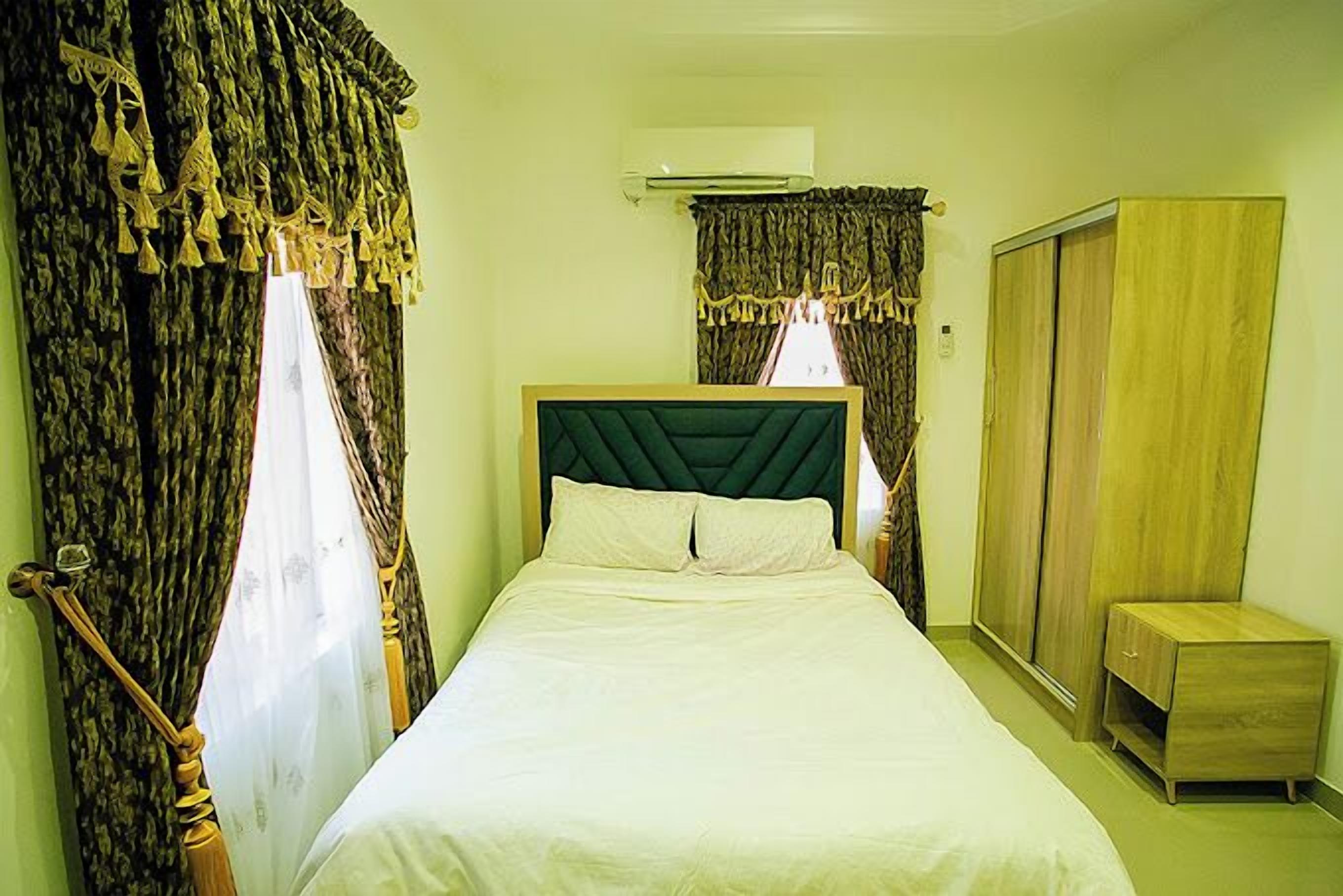 Een slaapkamer met een bed, gordijnen, een airconditioning en een kledingkast.