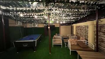 A pool table, seating area, and a wall with a textured pattern.