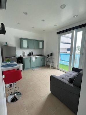 Enjoy a meal at the dining table, then relax on the sofa in the living area, which leads to a balcony with a pool view.