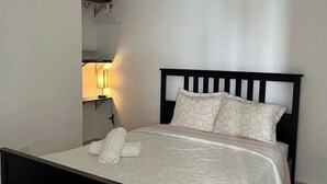 A neatly made bed with a black headboard and white bedding, a bedside lamp, and a towel on the bed. - Sweet Sunset 5 Playa Rompeolas, Aguadilla (Aguadilla)