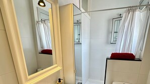 Un baño con lavamanos blanco, inodoro, ducha y espejo.