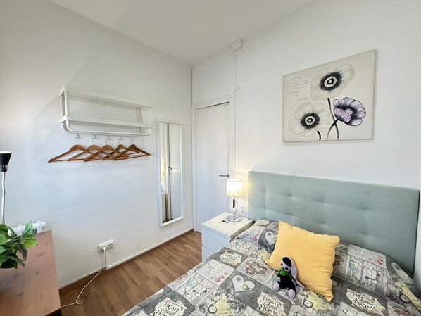 A bedroom with a bed, a bedside table, a hanging light, a wall-mounted air conditioner, and a window. - Rooms Rambla (Barcelona)