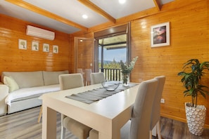 A wooden interior with a sofa, dining table, chairs, and a potted plant. - Recanto do Escalheiro (Vieira do Minho)