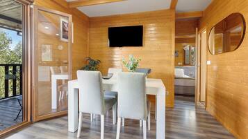 Ein Holzinterieur mit Essbereich, einem an der Wand befestigten Fernseher und einer Glastür zum Außenbereich.