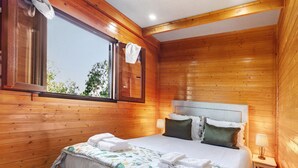 Ein Zimmer mit Holzwänden, einem Bett, einem Fenster und einem Nachttisch.