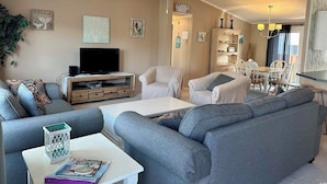 Un salon avec un canapé, des fauteuils, une table basse et un téléviseur.