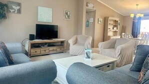 Un salon équipé d’un téléviseur à écran plat, de deux canapés gris, d’une table basse et d’une bibliothèque.