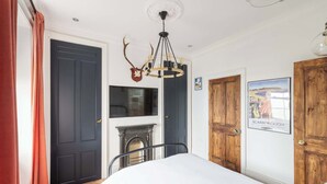 Un dormitorio con cama, chimenea, candelabro y dos puertas.