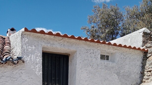 A rustic building with a tiled roof, a barred door, and a small window. - Cottage 'El Granero' with Shared Pool and Shared Garden (El Real De La Jara)