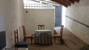 A room with a table and chairs, a washing machine, a staircase, and a view through a window. - Cottage 'El Granero' with Shared Pool and Shared Garden (El Real De La Jara)