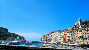 Une ville côtière aux bâtiments aux couleurs vives, un port de plaisance rempli de bateaux et un ciel d’un bleu limpide.